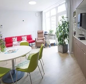 Heller Begenungsraum mit Tisch und Stühlen, Sofa und Küchenzeile.